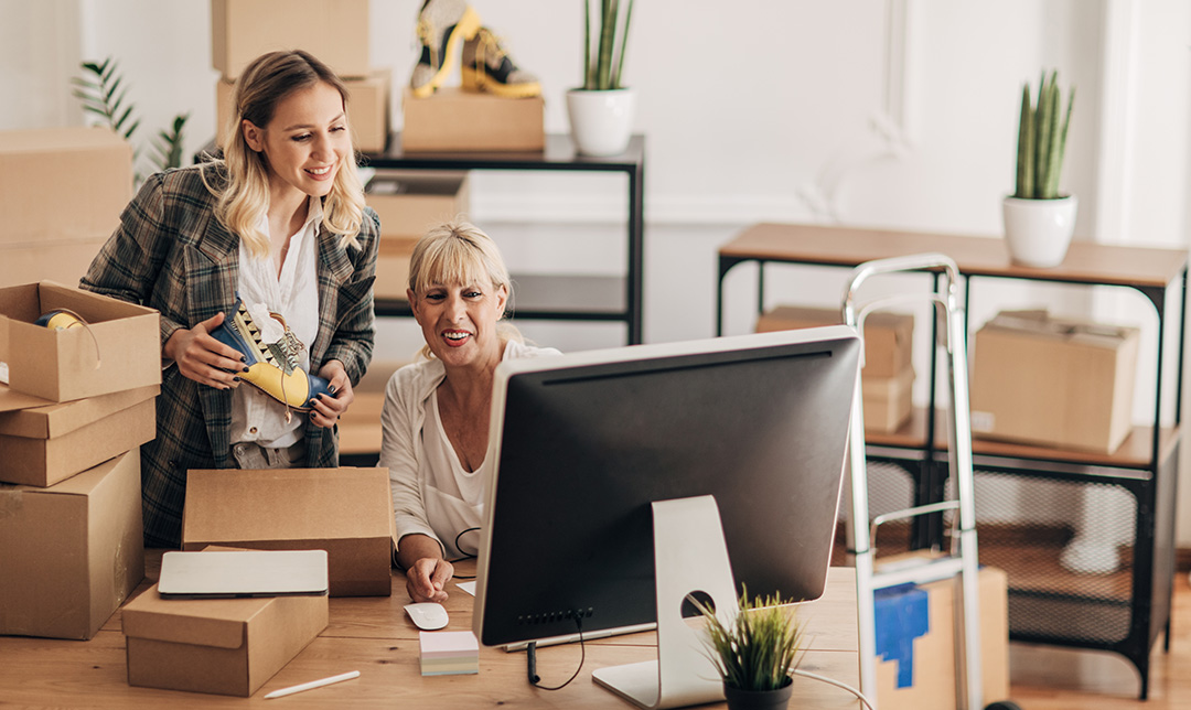 Photo of two office workers sitting at a table with open laptop